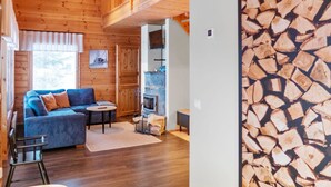 Ein gemütliches Blockhaus-Interieur mit Holzboden, einem blauen Sofa, einem kleinen Tisch und einem Kamin.