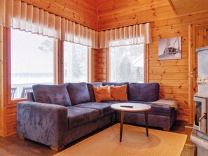 Een gezellig cabin interieur met een hoekbank, een kleine ronde tafel en een open haard.