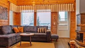 L’intérieur d’un chalet confortable, avec un canapé, une petite table ronde et une cheminée.