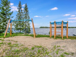 A playground with swings and a climbing structure near a lake. - Vuokatti villas ahma by Interhome (Sotkamo)