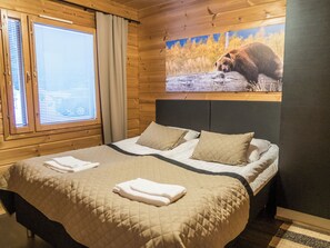 A room with a bed, a window with blinds, a painting of a bear on the wall, and a checkered floor. - Vuokatti villas susi by Interhome (Sotkamo)