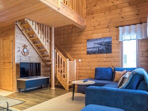 En inredning med träpanel, en trappa, en tv, en soffa och en tavla på väggen.
