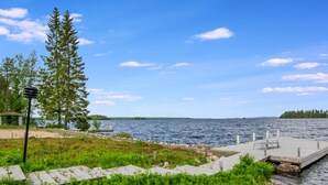 A lakeside view with a dock, grassy areas, and a small building. - Vuokatti villas kettu by Interhome (Sotkamo)