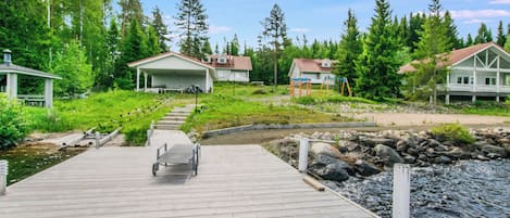 A wooden dock leading to a row of houses with a small stream in the background.