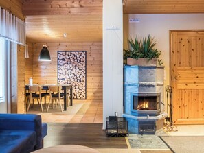 Ein gemütliches Interieur mit Holzbalkendecke, Kamin, Essbereich und einer großen Holztür.