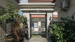 A courtyard with a glass door entrance, potted plants, and a stone statue. - Samurai Sanur Hotel (Denpasar)