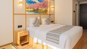 A hotel room with a bed, a nightstand, a painting of a mountain landscape, and a wooden floor. - Samurai Sanur Hotel (Denpasar)