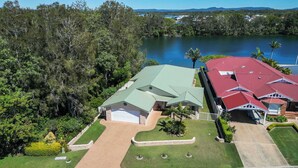 A residential property with a green roof, a garage, and a well-maintained lawn. - Waterfront - Kolora Lake House - Oceanstays (Yamba)