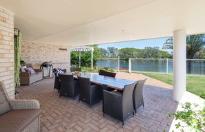 Une terrasse extérieure avec une table et des chaises, un barbecue et une vue sur un lac.