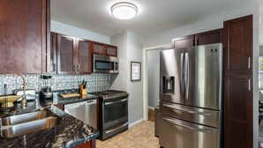 A modern kitchen with stainless steel appliances, dark wooden cabinets, and a tiled backsplash. - Hot Tub BBQ Retreat Spacious Backyard Pet-friendly (North Augusta)