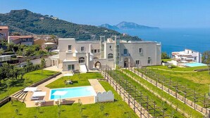 Una villa moderna con piscina, jardín y vista al mar.