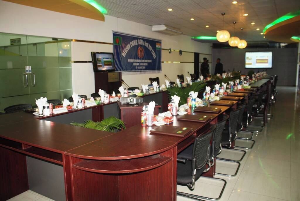 A conference room with a long table, chairs, a podium, and a banner on the wall.