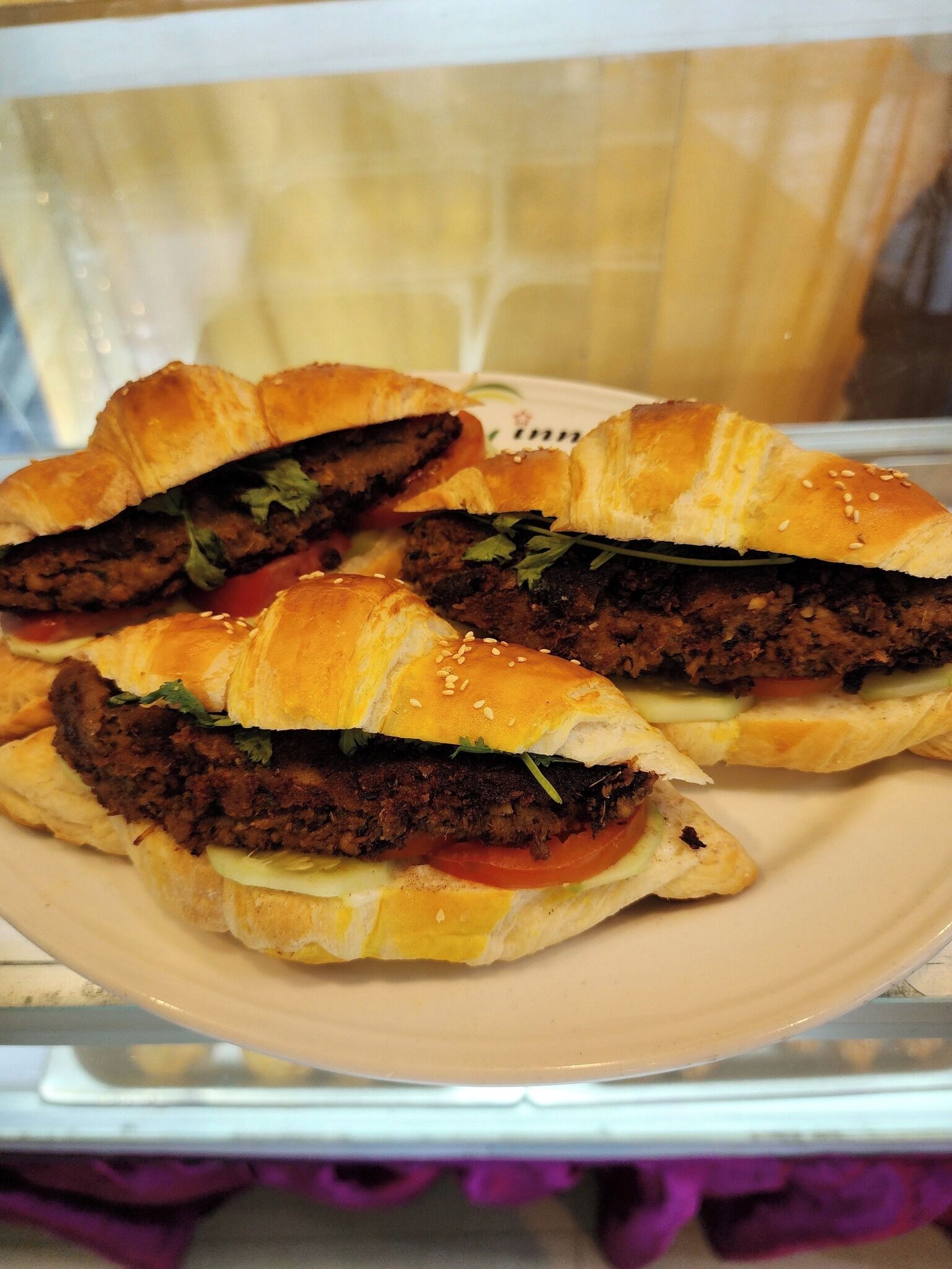 A plate with three sandwiches, each cut in half, revealing layers of meat, vegetables, and sauce.