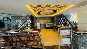 A modern café lounge with a geometric ceiling design, marble flooring, and a glass display case. - City Inn Limited Khulna (Khulna)