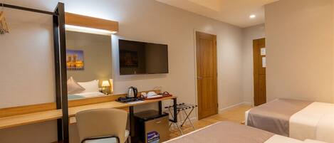 Una habitación de hotel con cama, escritorio, silla, televisor, armario y puerta.