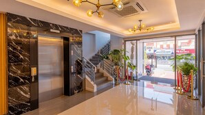 A modern hotel lobby with marble walls, a staircase, and a glass entrance leading outside. - Doña Manor Boutique Hotel (Olongapo)
