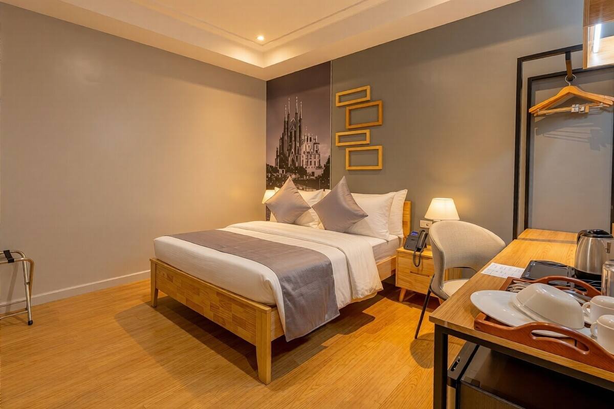 Une chambre d’hôtel avec un lit, une table de chevet, une lampe et une chaise en bois.