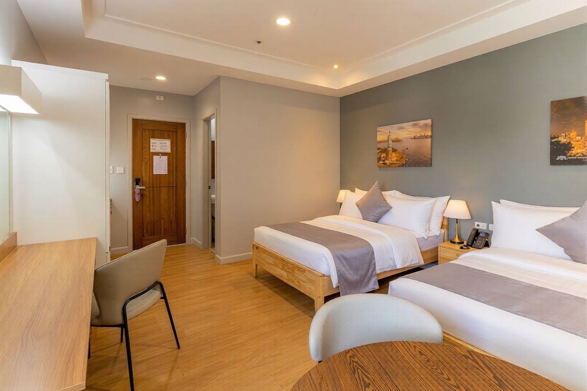 Une chambre d’hôtel avec deux lits, un bureau et une chaise.