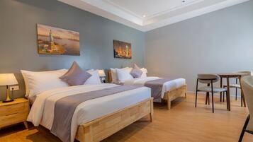 A hotel room with two beds, a desk, and a chair.