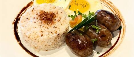 A plate with rice, a fried egg, and sausages.
