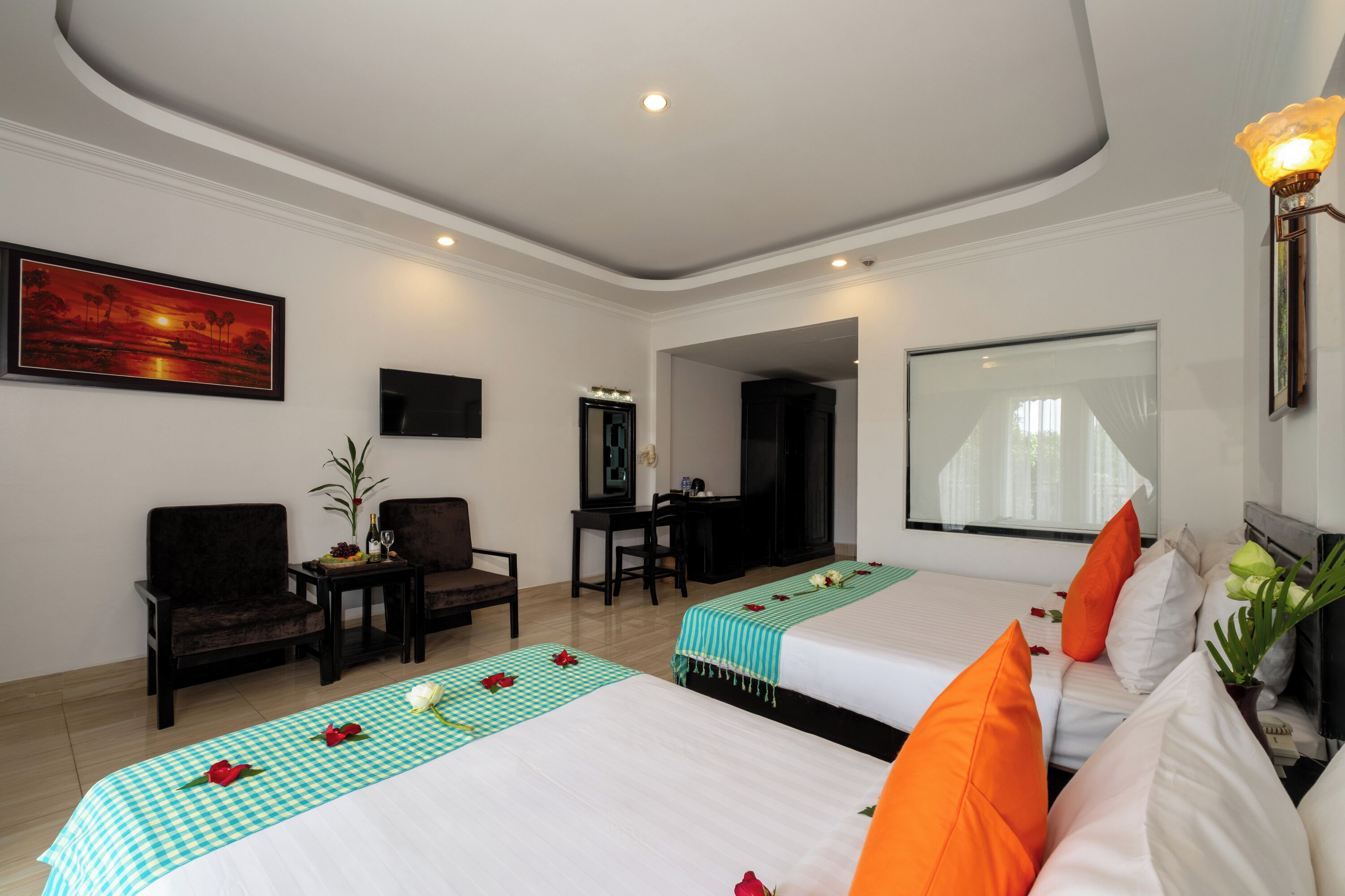 A hotel room with two beds, a desk, a chair, a TV, and a large window.