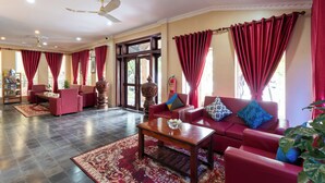 Un salón amplio con sofás rojos, una mesa de centro y un gran ventanal con cortinas rojas.