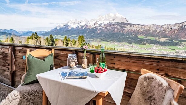 A wooden deck with a table set for dining, overlooking a mountainous landscape. - Penzing by Interhome (Sankt Johann in Tirol)