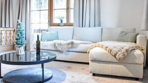 A cozy living room with a white sofa, a glass coffee table, and a small Christmas tree. - Penzing by Interhome (Sankt Johann in Tirol)
