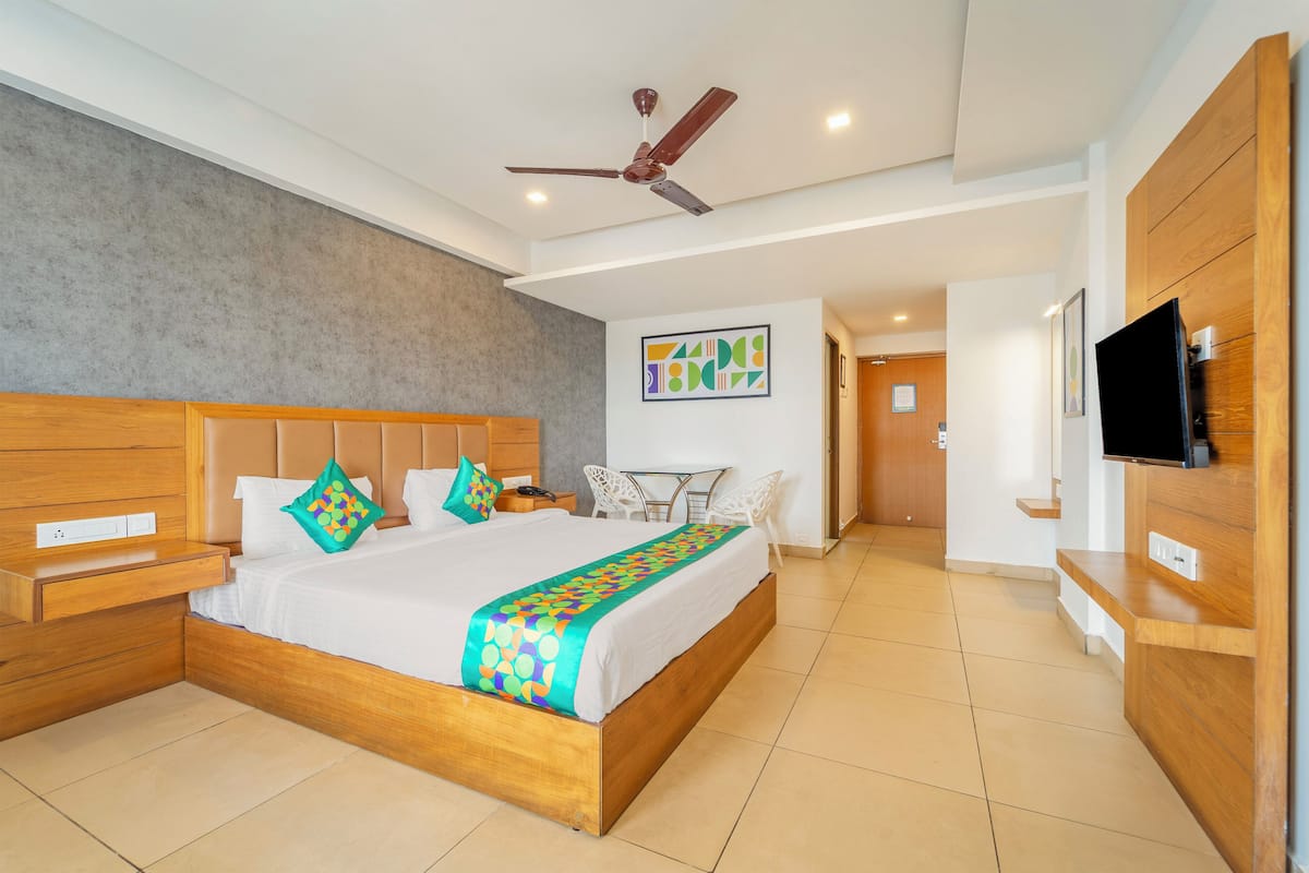 Ein modernes Hotelzimmer mit einem Holzbett, einem Deckenventilator, einem Fernseher und einem Schreibtisch.