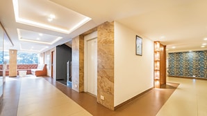 Un hall d’hôtel moderne avec une colonne en marbre, un canapé, une porte et un mur orné de motifs.