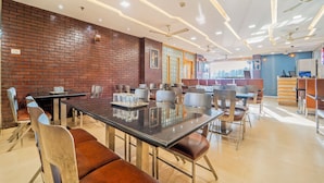 Un restaurant moderne avec des murs en briques, de nombreuses tables et des ventilateurs de plafond.