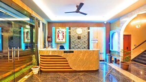 A hotel reception area with a marble counter, a ceiling fan, and a staircase. - Hotel The Crystal (Māvli)