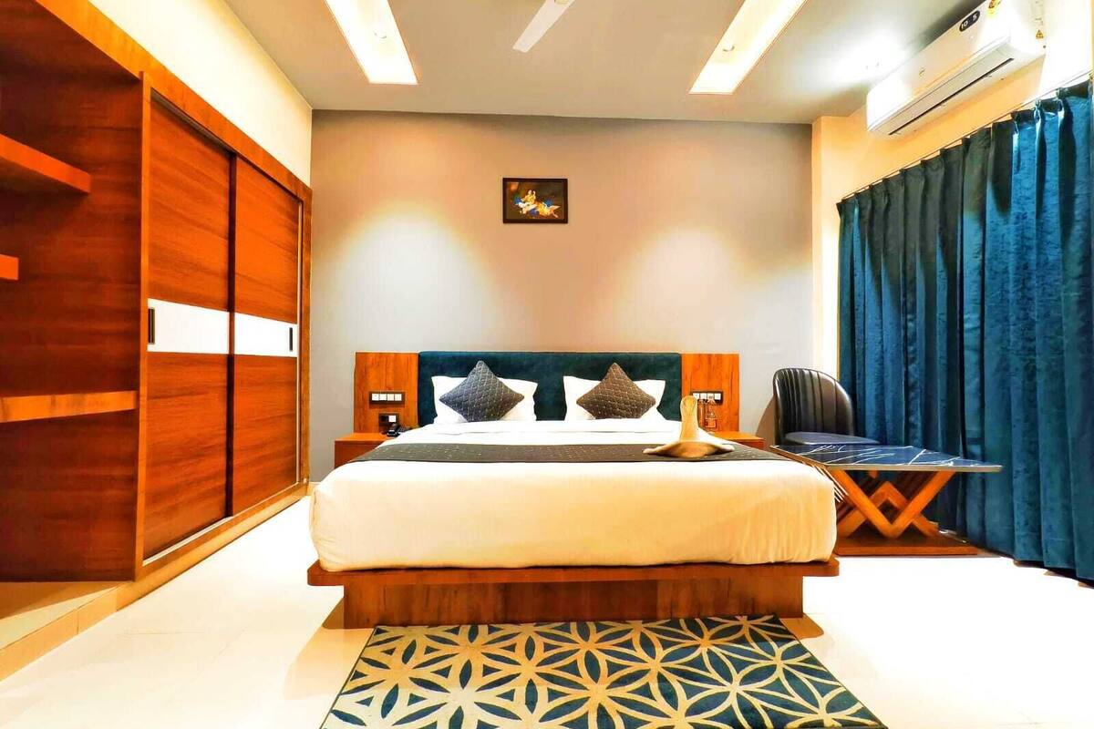 A modern hotel room with a large bed, wooden wardrobe, and a ceiling fan.