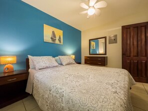 Ein Schlafzimmer mit Bett, Nachttischen, einem Spiegel und einer Tür.
