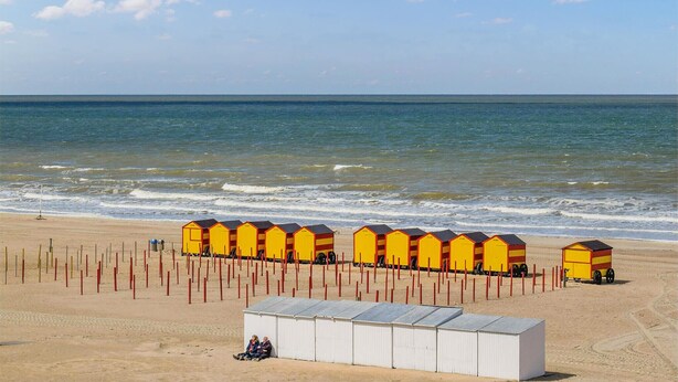 Une plage avec des cabanes de plage jaunes et un bâtiment blanc.