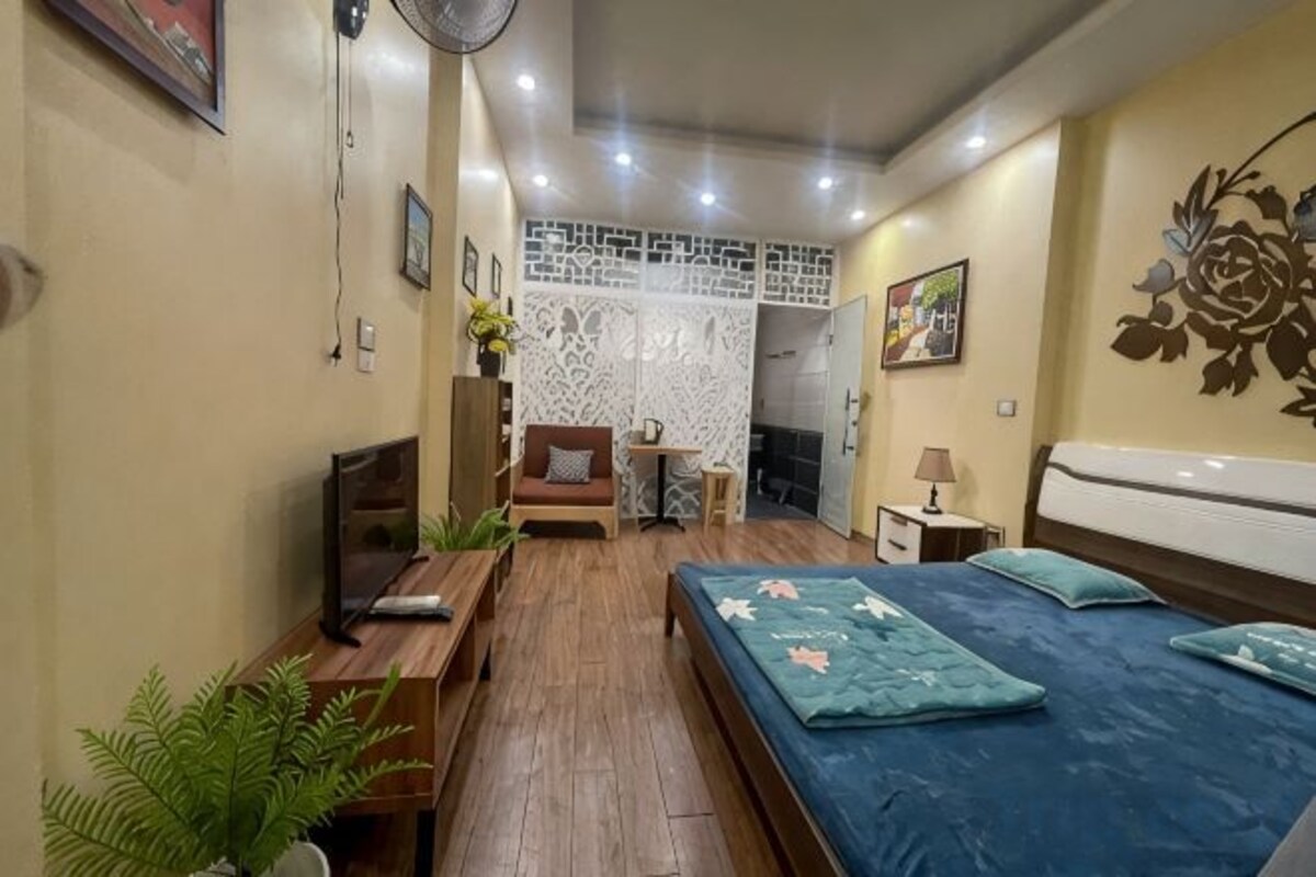 Una habitación de hotel con cama, escritorio, silla, televisor y ventana.