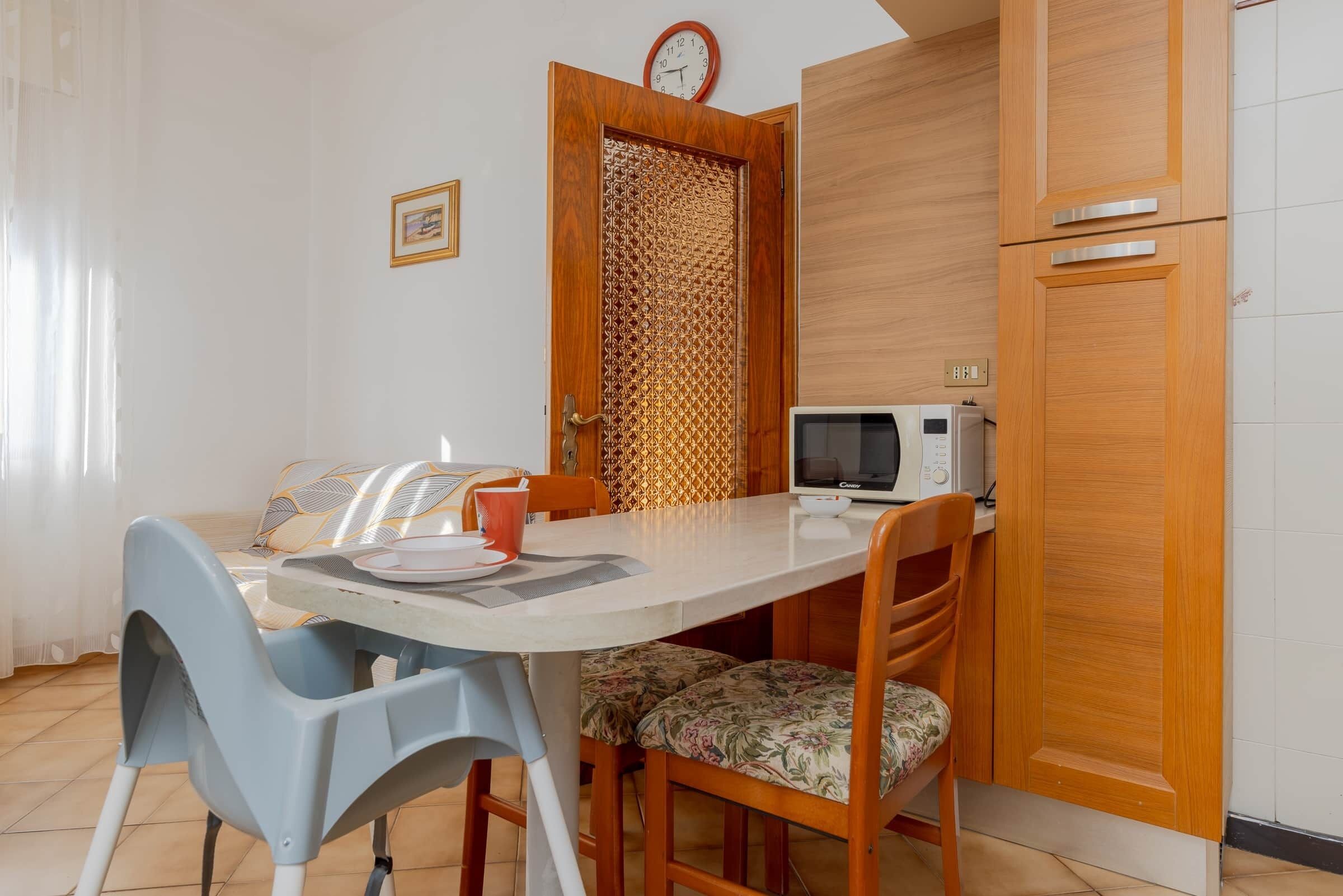 Una cucina funzionale con forno a microonde, mobili in legno e un tavolo con sedie.