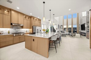 Une cuisine moderne avec des meubles en bois, un plan de travail en marbre et des luminaires suspendus.