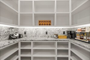 Une cuisine dotée de plans de travail en marbre, d’une machine à café, d’un mixeur et d’une cafetière.