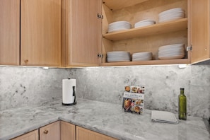 A kitchen with wooden cabinets, marble countertops, a coffee maker, a cookbook, a towel, and a bottle. - Festive Villa in Richardson/Dallas (Richardson)