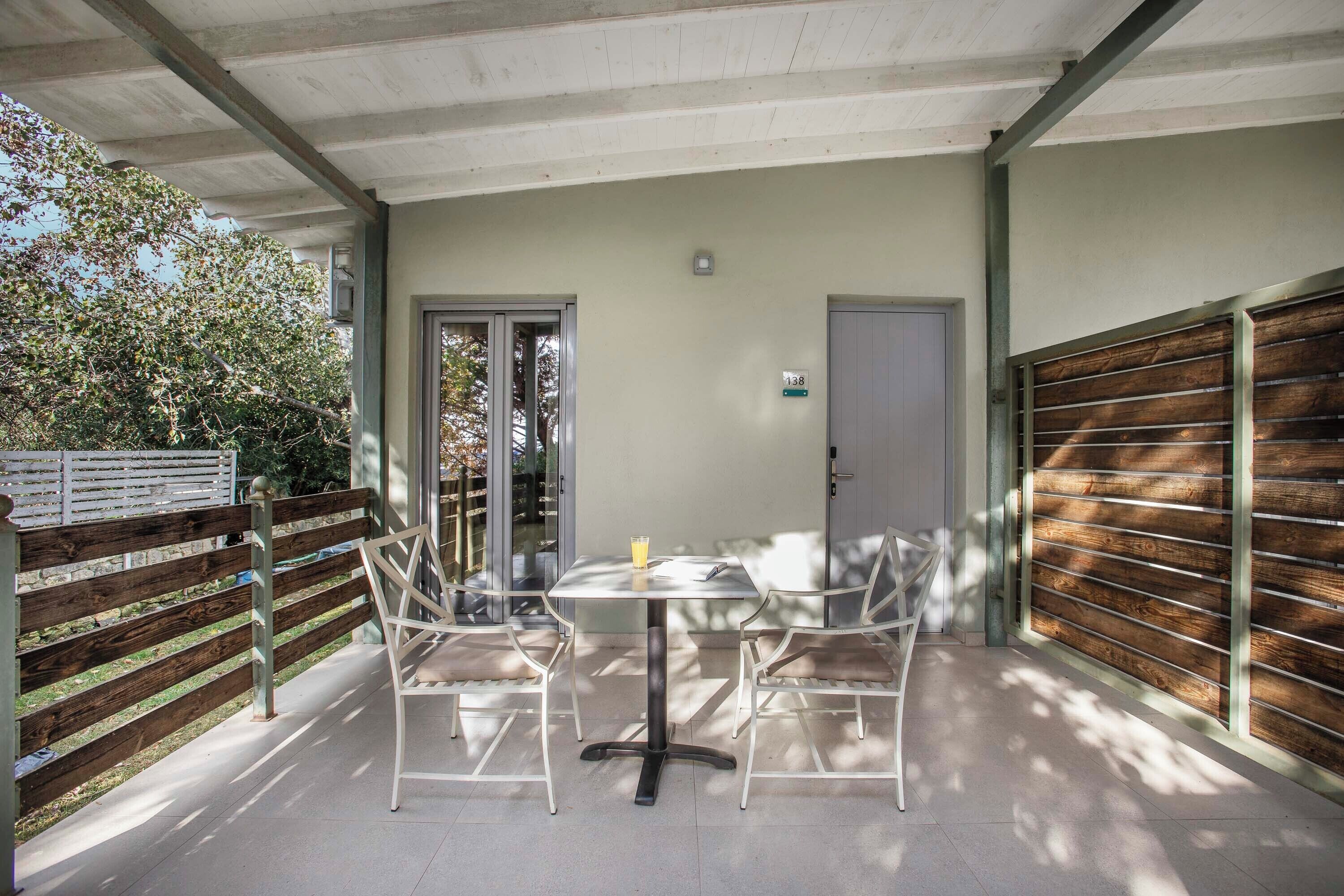 Une terrasse extérieure avec une table et des chaises, une porte et une clôture en bois.