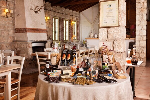 Un coin repas rustique avec des murs en pierre, des tables en bois et une variété de plats et de boissons présentés sur une table.