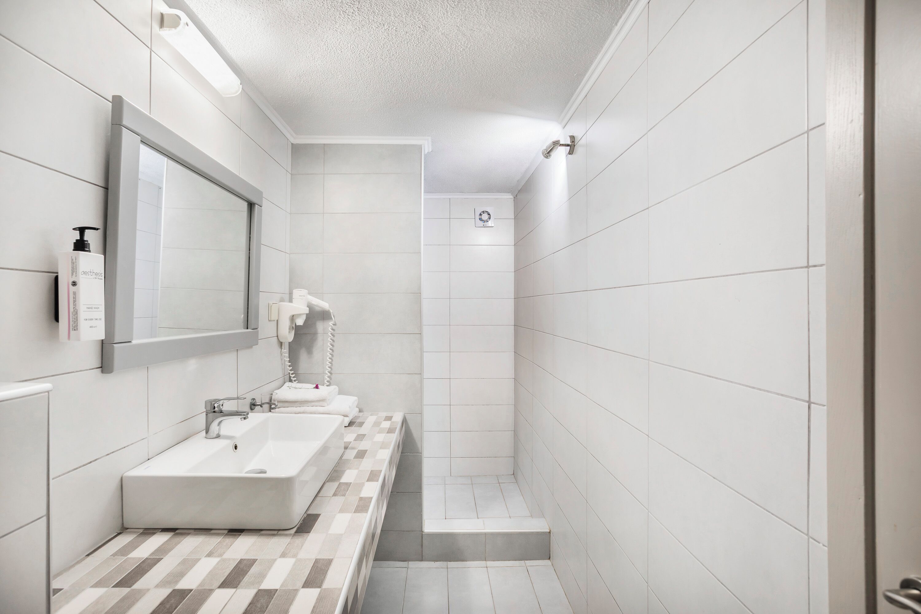 A modern bathroom with a large mirror, a sink, and a shower area.