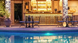 A poolside bar area with a wooden pergola, bar counter, and seating. - Petrino Eco Village (Kassandra)
