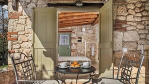 A stone building with a wooden door and a table with a plate of pastries. - Petrino Eco Village (Kassandra)