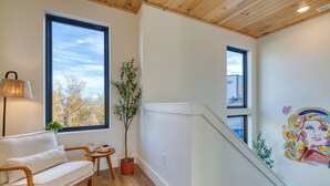A modern interior with a wooden ceiling, a white sofa, a small table with a plant, and a mural on the wall. - Smoky Mountain Cabin with Indoor Pool + Hot Tub + Views | Dolly's Dreamhouse (Sevierville)