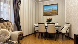 Ein Esszimmer mit einem Holztisch, vier Stühlen, einem Bild an der Wand und einem Fenster mit Vorhängen.