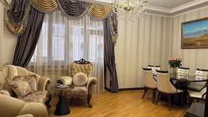 Ein luxuriöses Wohnzimmer mit einem gepolsterten Sessel, einer Couch, einem Esstisch mit Stühlen und einer Chandeliebre.
