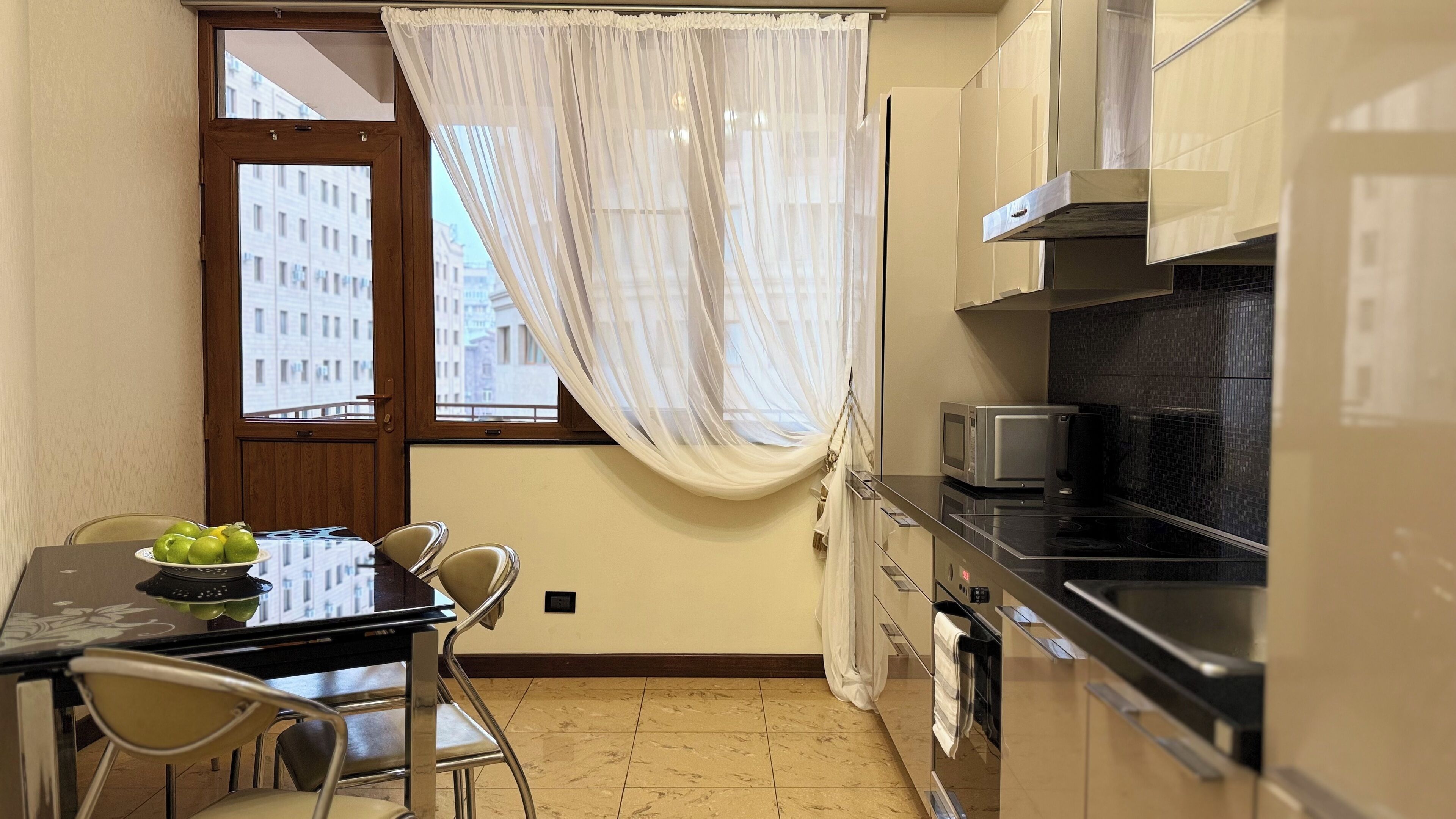 A compact kitchen with a dining area, a microwave, and a view of the city through a window.