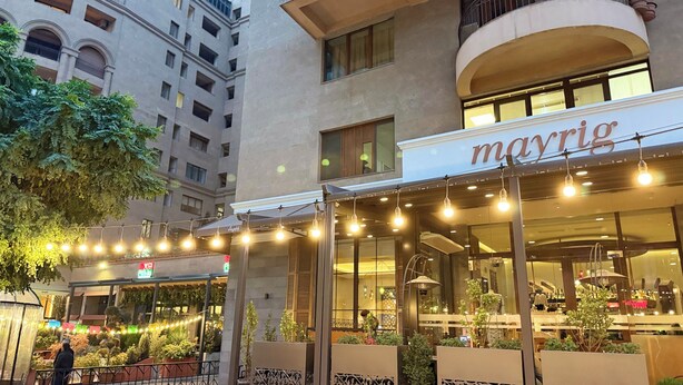Ein Mayrig Restaurant mit Außenbereich, umgeben von Gebäuden und Grünflächen.